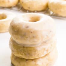 A stack of three air fryer donuts since in front of more donuts in the background.