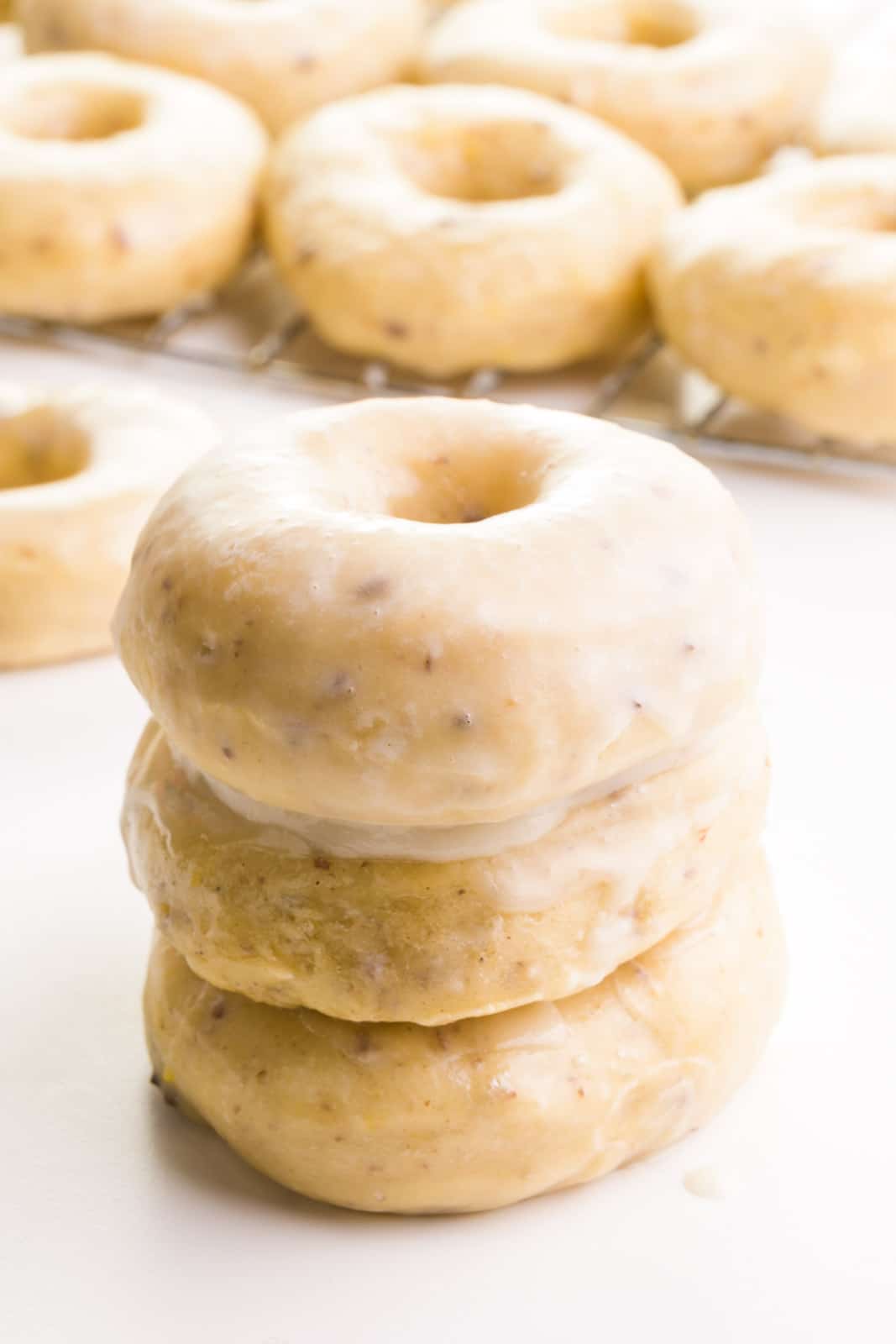 A stack of three air fryer donuts since in front of more donuts in the background.