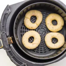 Donuts are in an air fryer basket getting ready to be fried.