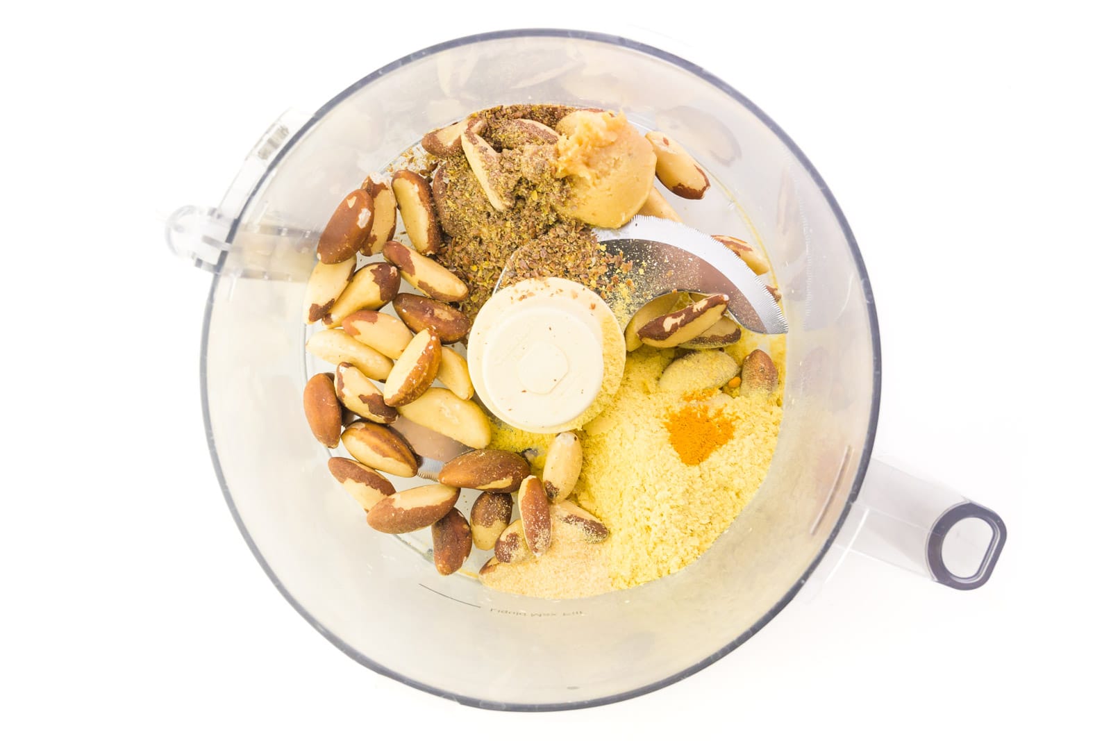Brazil nuts and other ingredients are in a food processor.