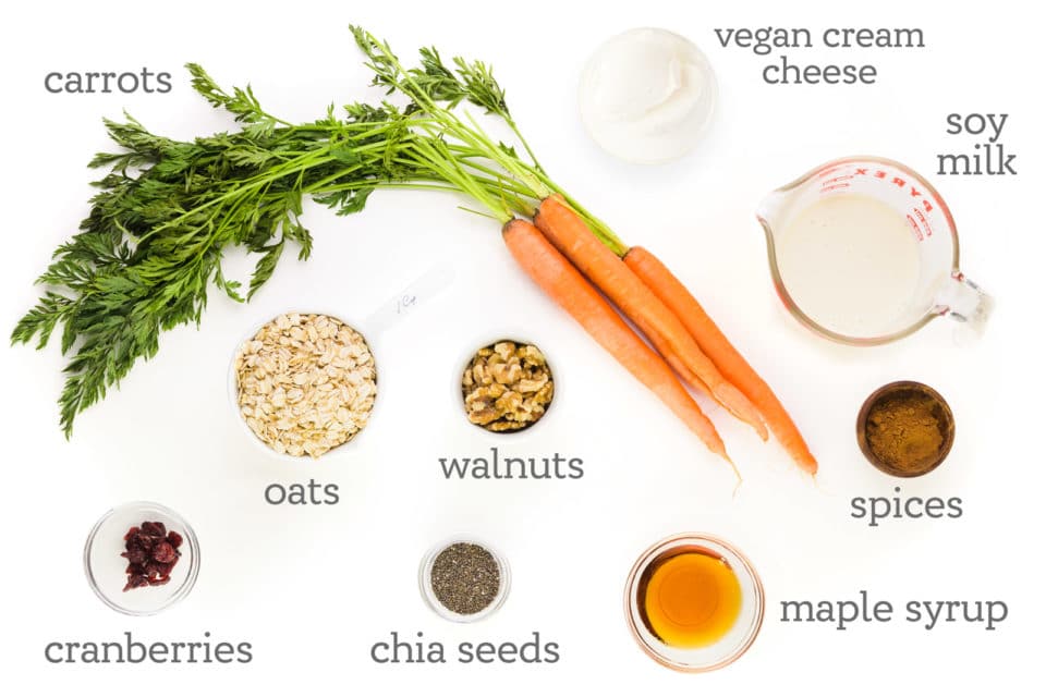 Ingredients are on a counter. The labels next to them read, "vegan cream cheese, soy milk, spices, maple syrup, chia seeds, walnuts, oats, cranberries, and carrots."