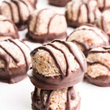 A stack of chocolate coconut macaroons has many more of the sweet treats behind it.
