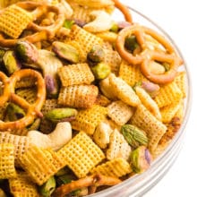 A large bowl is full of gluten-free Chex mix, featuring pretzels, nuts, and more.