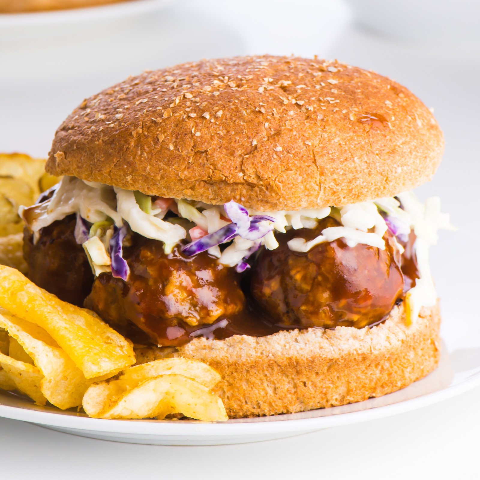 Closeup of a lentil BBQ meatball sandwich with a whole wheat bun
