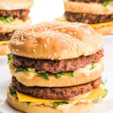 A vegan Big Mac sandwich sits in front of two more in the background.