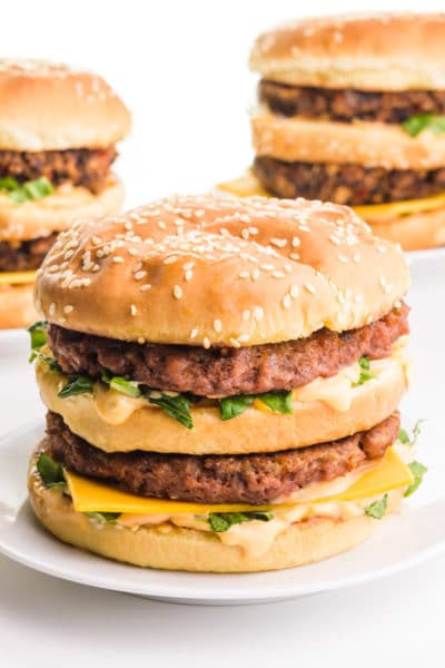 A vegan Big Mac sandwich sits in front of two more in the background.
