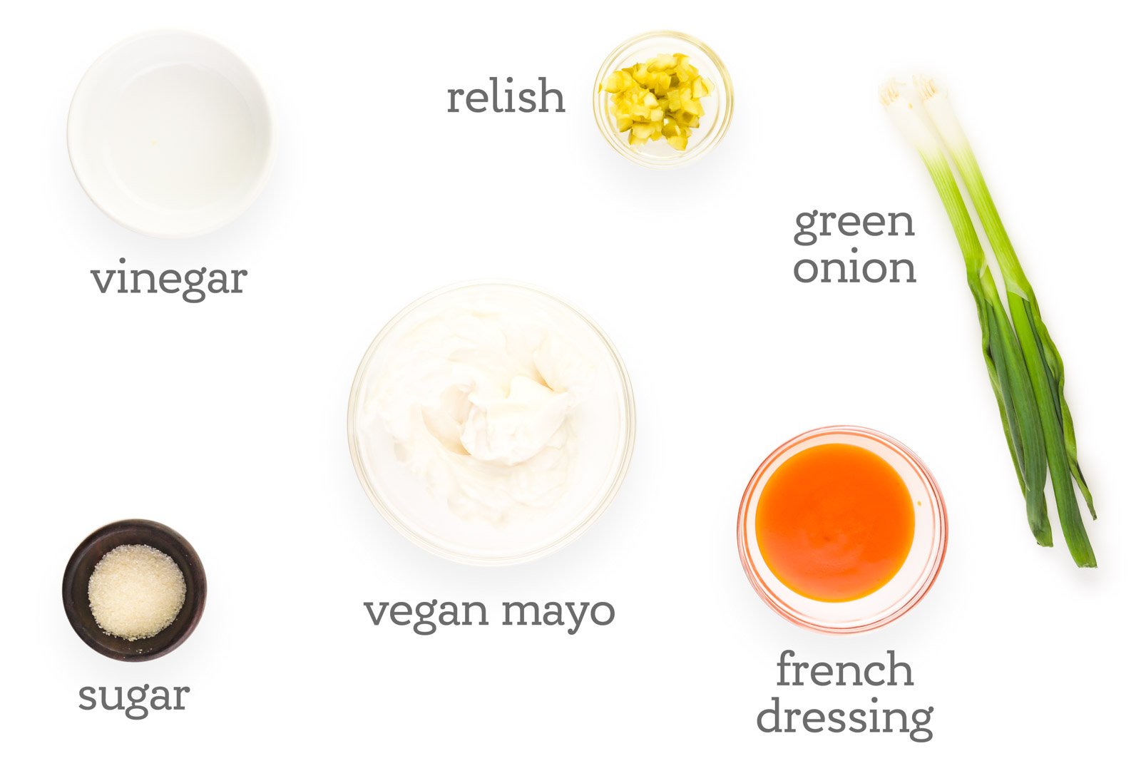 Ingredients are laid out on a table. The labels read, "vinegar, relish, green onions, French dressing, vegan mayo, sugar."