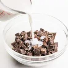 Milk is being poured into a bowl with chocolate chunks.