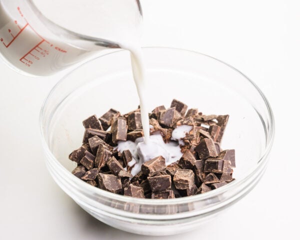 Milk is being poured into a bowl with chocolate chunks.