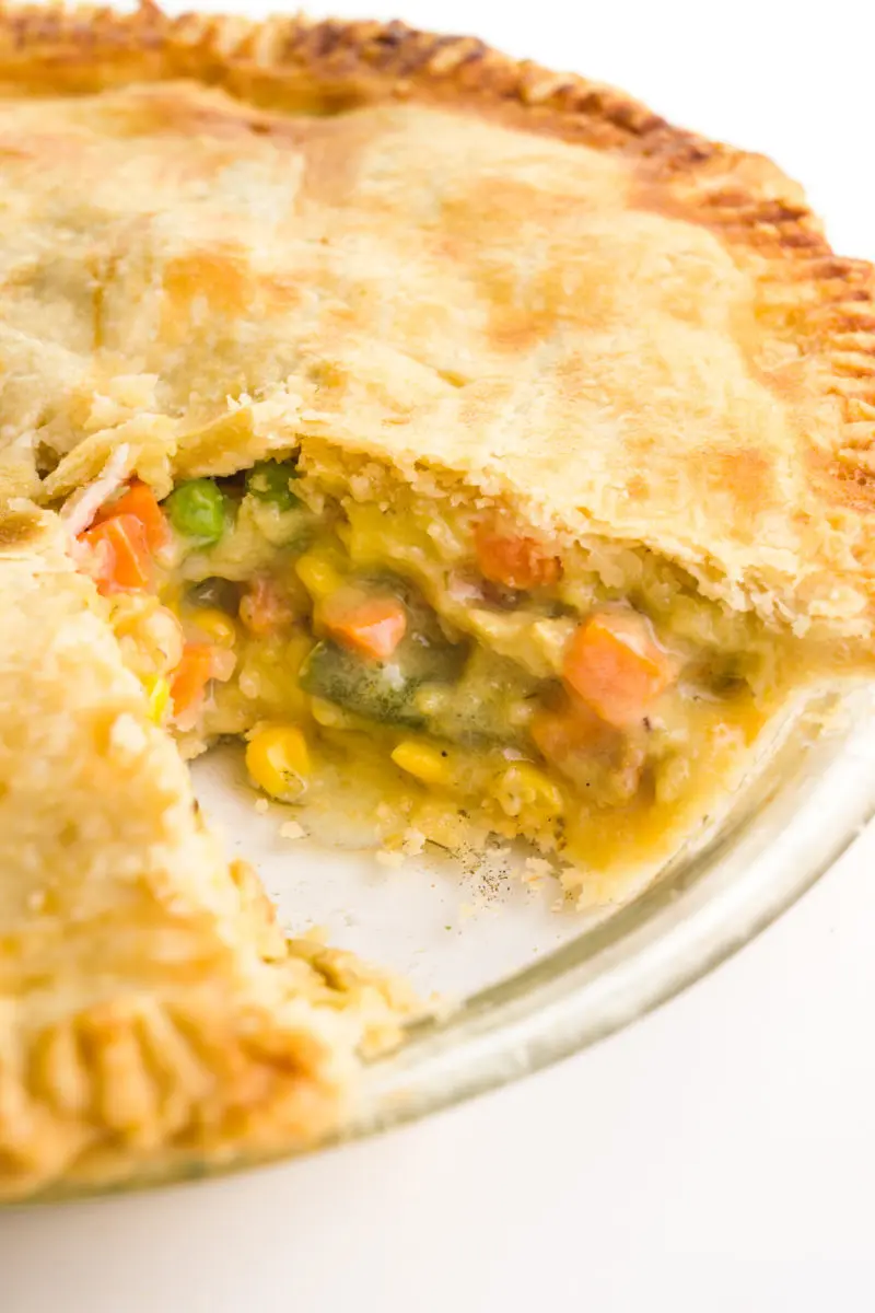A savory pot pie has a slice cut out revealing vegetables and vegan chicken inside.
