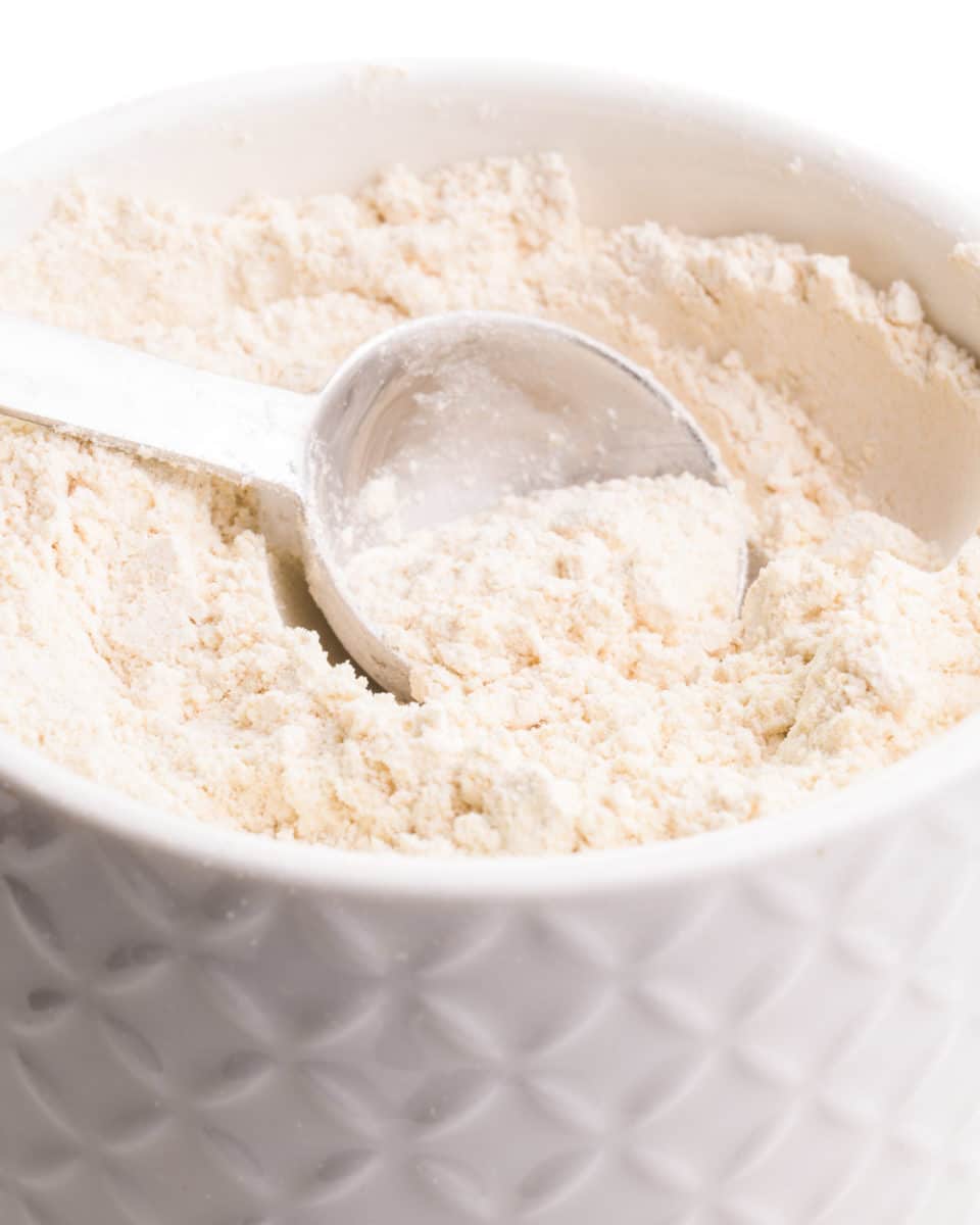 A measuring spoon sits in a bowl full of whole wheat pastry flour.