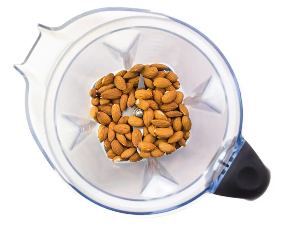 Looking down on a blender with raw almonds in the bottom.