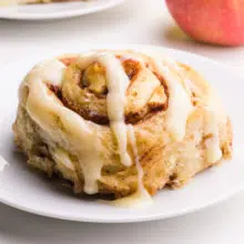 An apple cinnamon roll sits on a plate