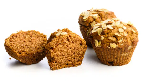 An applesauce muffin is sliced in half with 2 more whole muffins to the right.