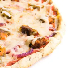 A cassava flour pizza crust has toppings like red sauce and cheese on top of it.