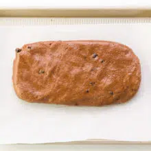 Looking down on a loaf of cookie batter shaped into a log on a baking pan.