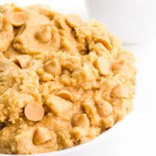 A bowl holds edible peanut butter cookie dough with peanut butter chips. There's a bowl of peanut butter in the background.