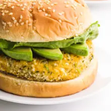 A closeup of a hemp burger on a bun with avocado slices and lettuce.