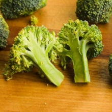 Broccoli has been cut into florets and one of the larger florets has been cut in half.