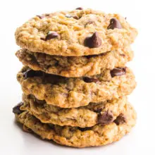A stack of vegan oatmeal chocolate chip cookies sits on a white counter.