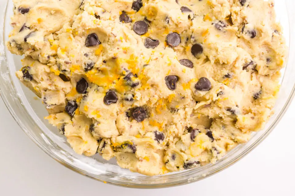 Looking down on a bowl full of cookie dough shows chocolate chips and flecks of orange zest.