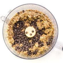 The energy balls meal is in a bottom of a food processor with chocolate chips.