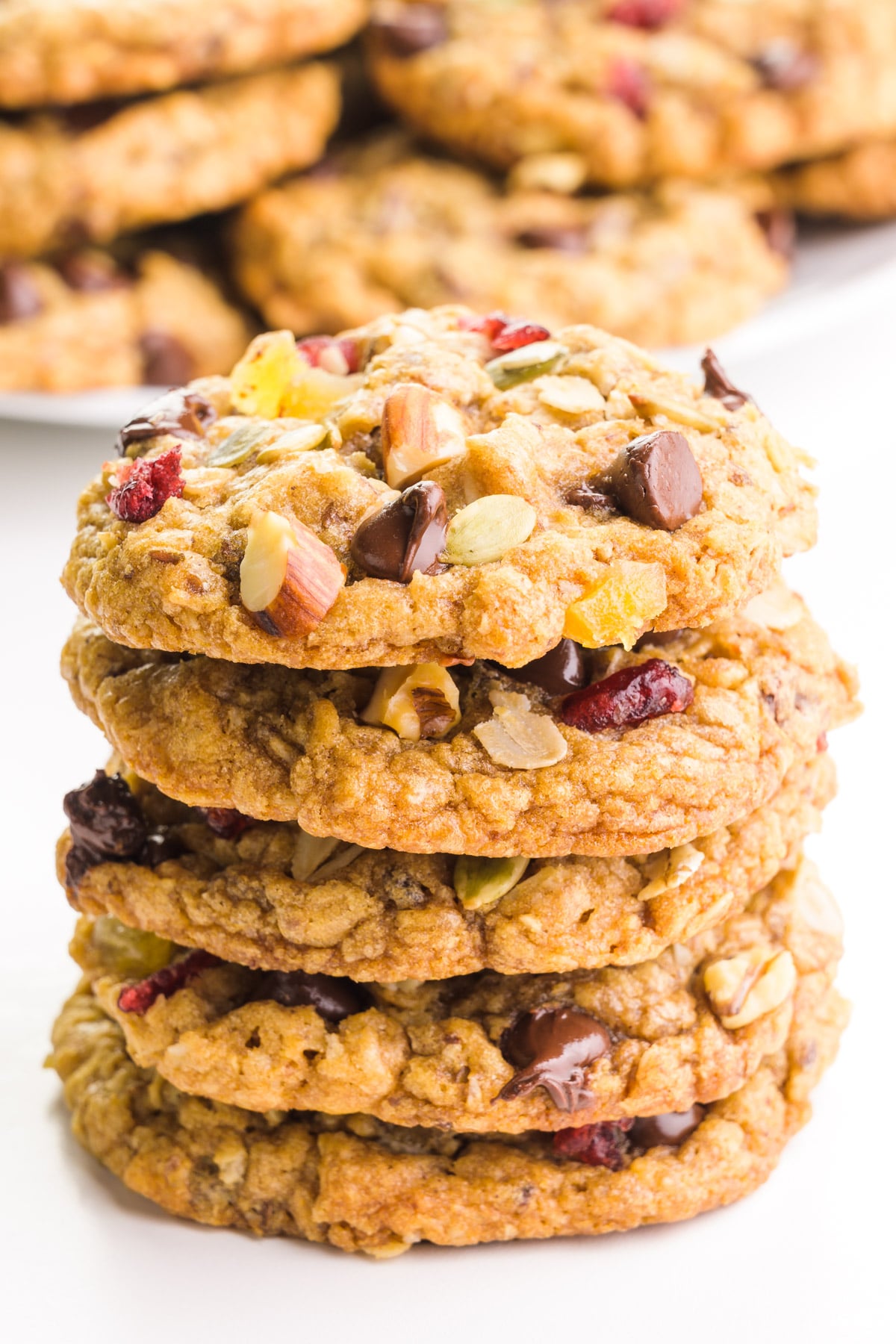 A stack of cookies sits in front of a plate of more cookies.