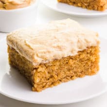 A slice of peanut butter cake with frosting sits on a plate.