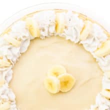 Looking down on a banana cream pie with whipped cream fluted around the edges and slices of fresh banana on top.