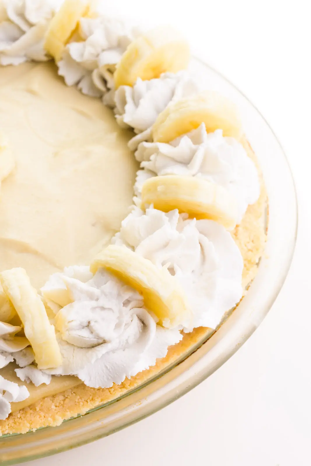 Looking down on the edge of a banana cream pie with decorative coconut cream and banana slices on top.