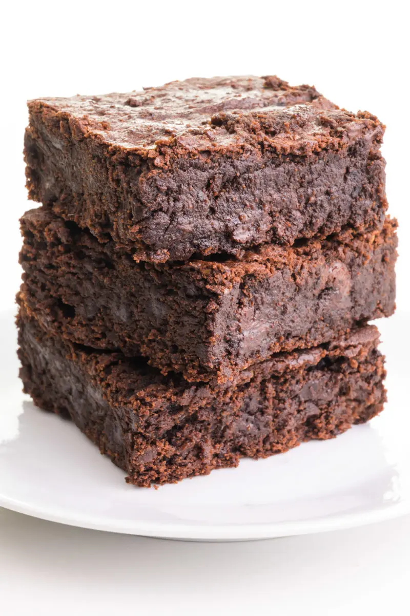 A stack of 3 black bean brownies sit on a plate.