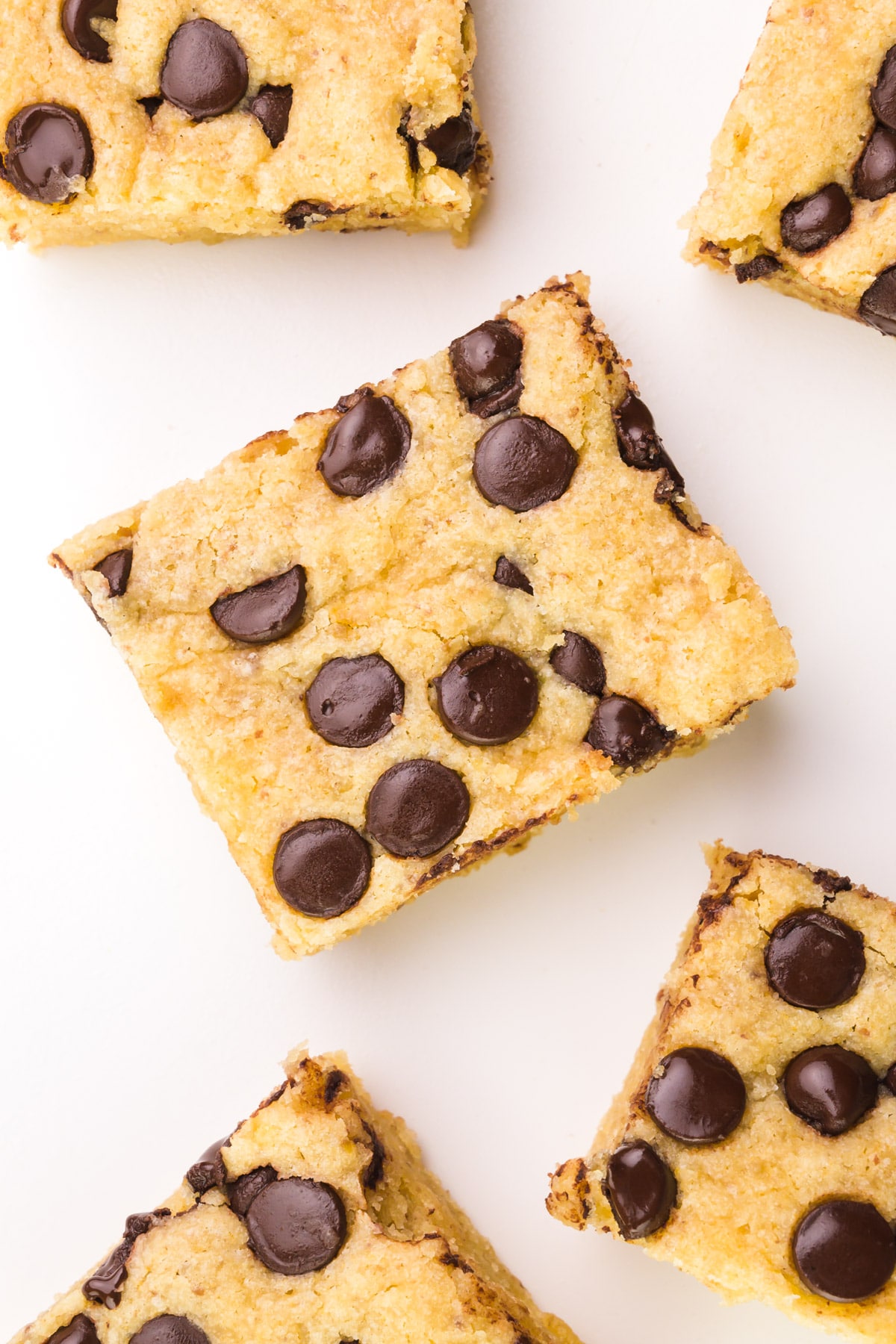 Looking down on a slice of vegan blondie with chocolate chips on top. There are more slices around it.