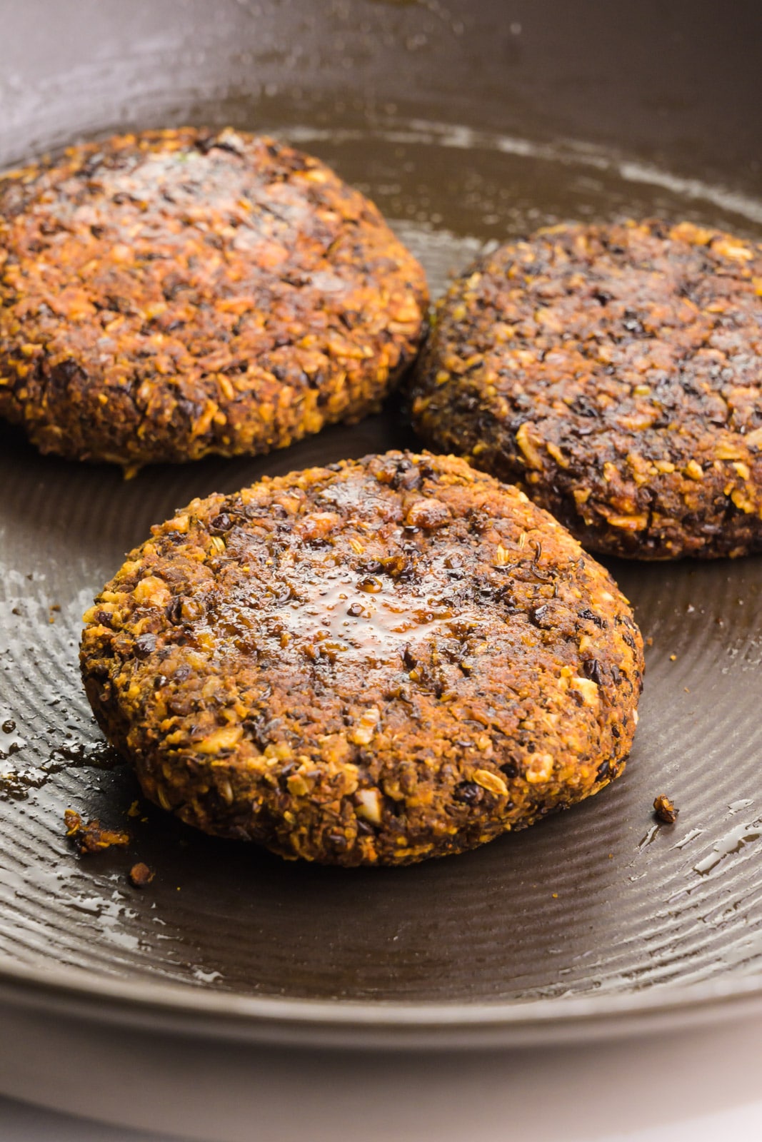 Vegan breakfast sausage patties are being cooked in a skillet.