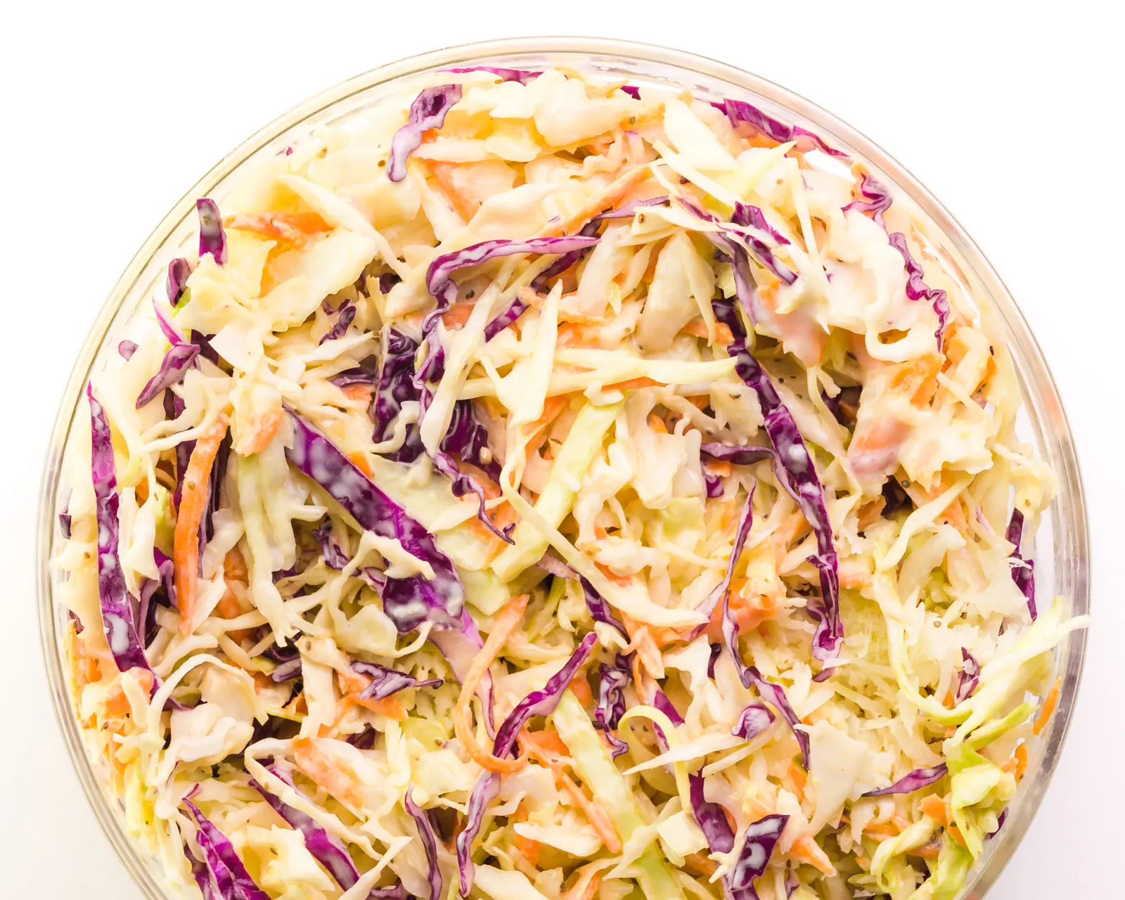 Looking down on a bowl of vegan coleslaw, showing shredded red and green cabbage.