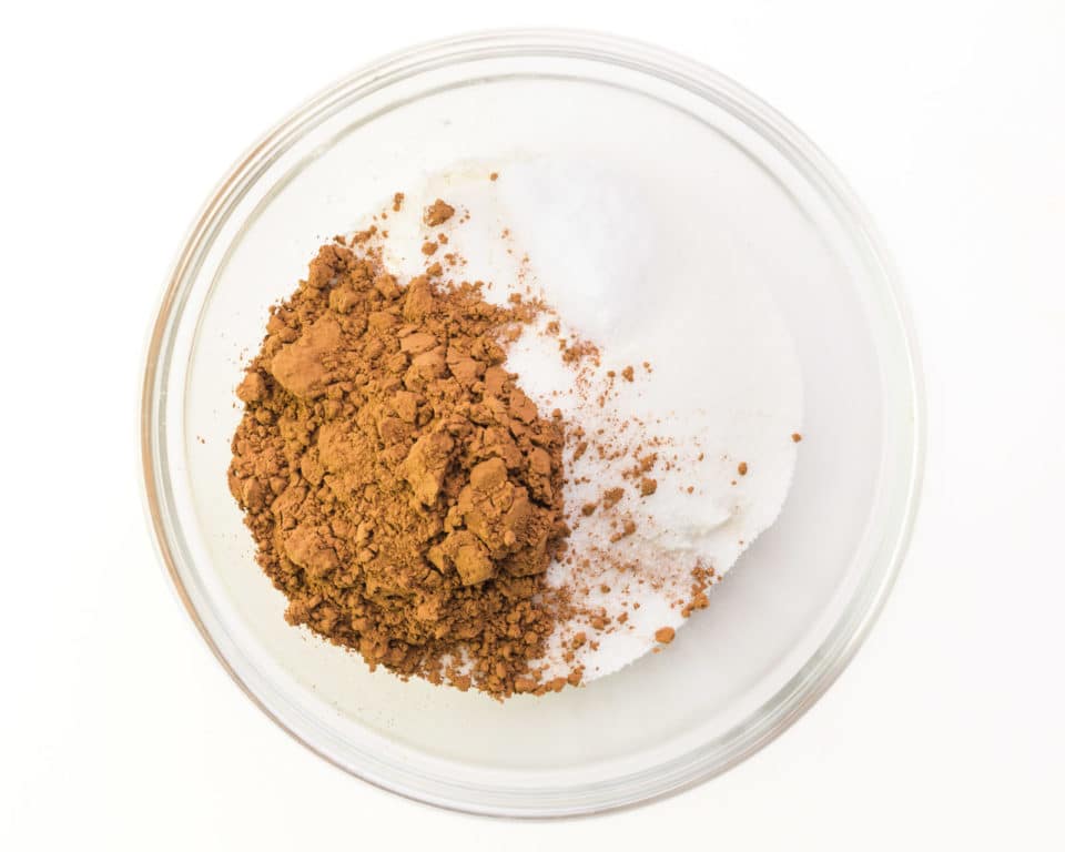 A flour mixture is combined with cocoa powder in a small glass bowl.