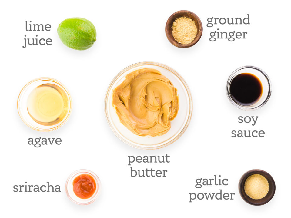 Ingredients are arranged on a white counter. The text reads, "lime juice, ground ginger, soy sauce, peanut butter, garlic powder, sriracha, and agave.