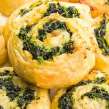 A spinach pinwheel sits on top several other pinwheels.