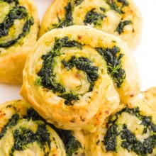 Looking down on a pinwheel pastry infused with spinach. It sits on top of several other of the pastries.