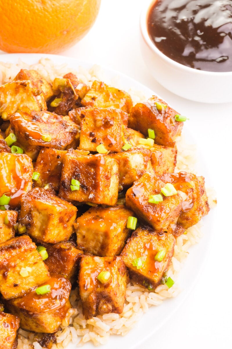 Looking down on a plate of orange tofu on a bed of rice.