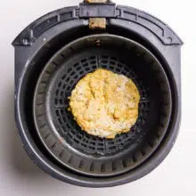 A fried tofu patty is in an air fryer basket.