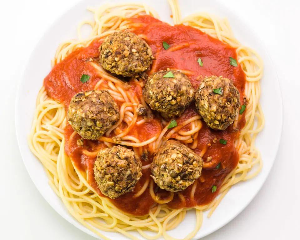 Looking down on a plate of spaghetti topped with lentil meatballs.