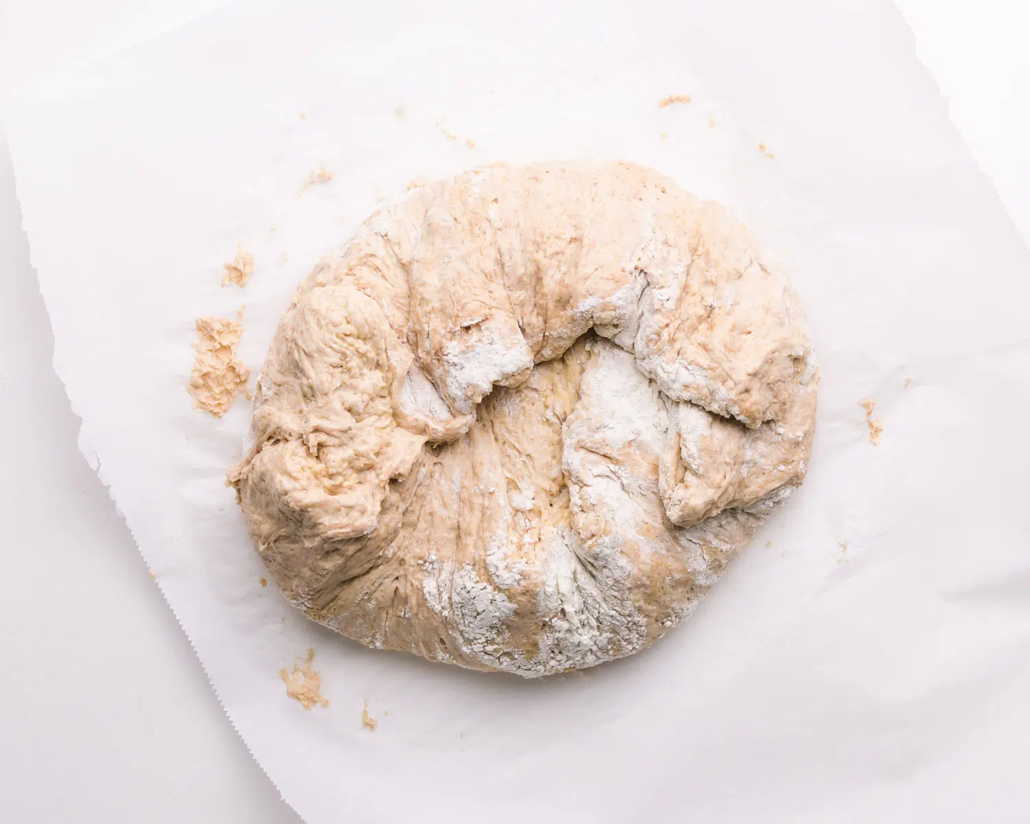 A ball of dough sits on a sheet of parchment paper.