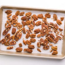 Pecans have been toasted on a baking sheet.