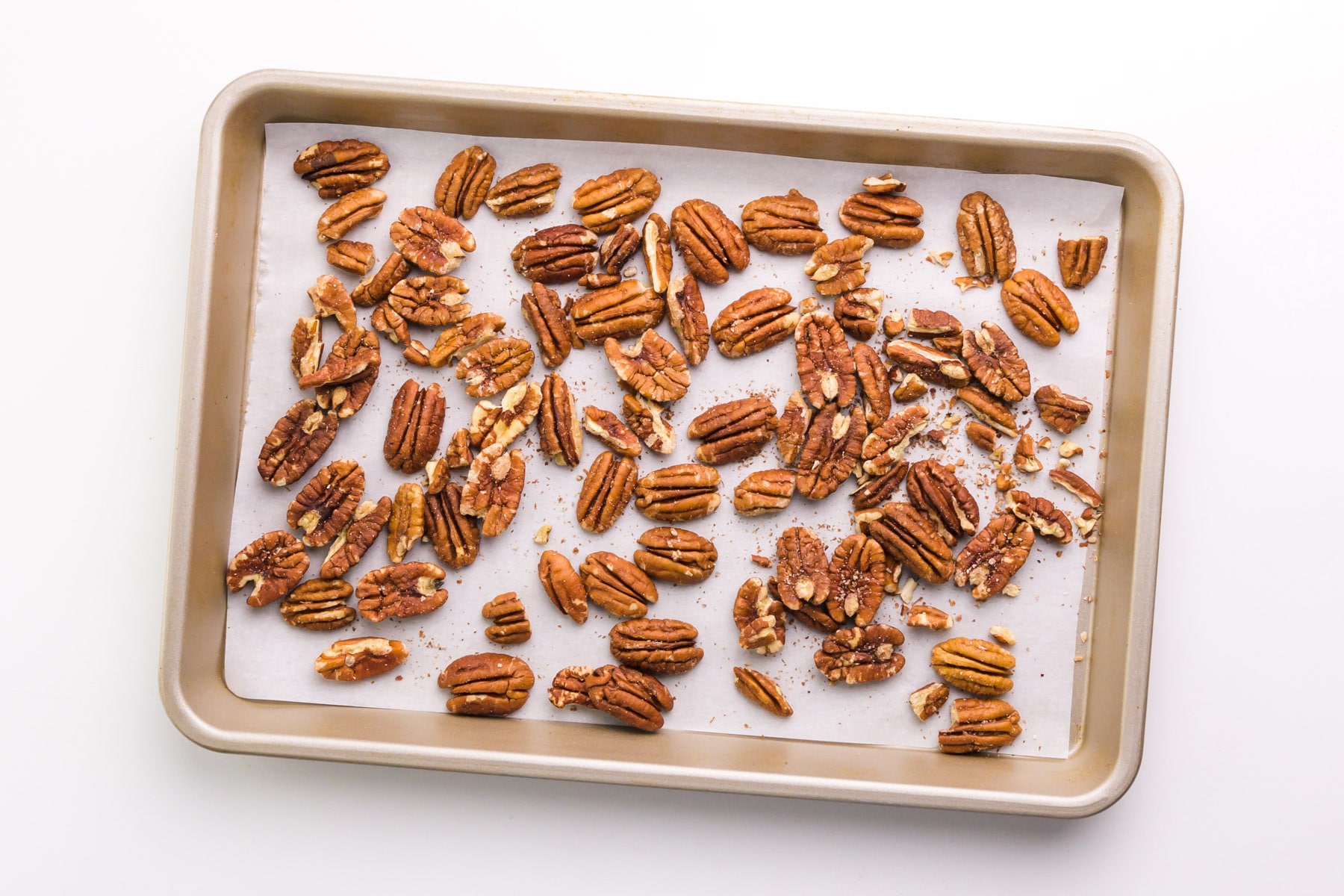 Pecans have been toasted on a baking sheet.