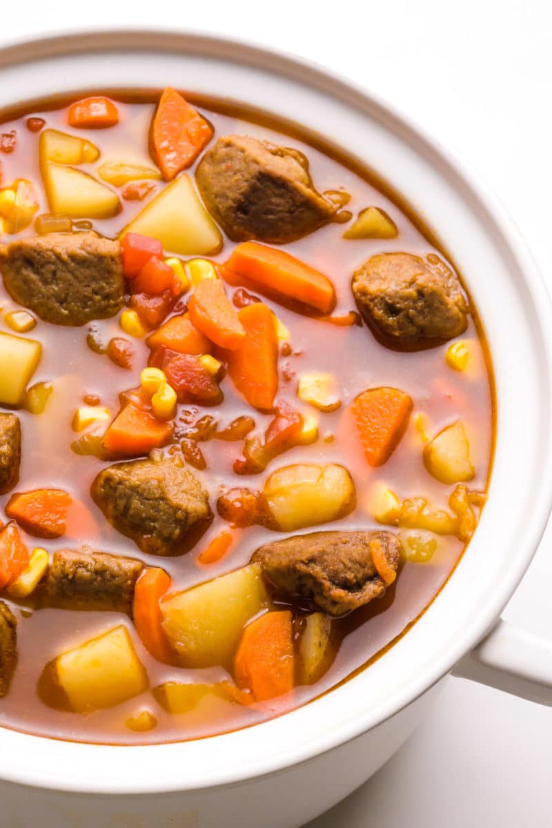A pot full of vegetable stew shows carrots, potatoes, and vegan beef.
