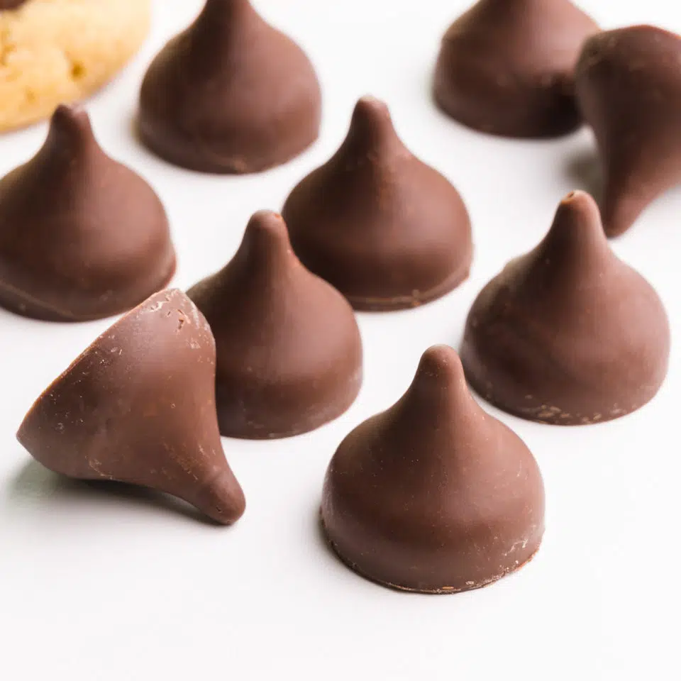 Several vegan chocolate kisses are on a white counter.
