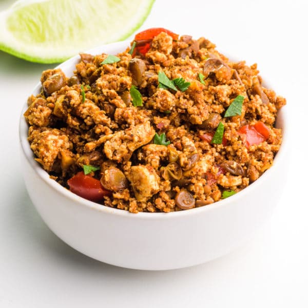 A bowl of vegan chorizo sits in front of a slice of lime.