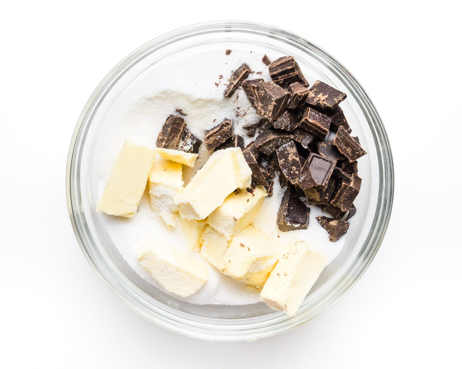 Ingredients are in a glass bowl, including chocolate, sugar, and vegan butter.