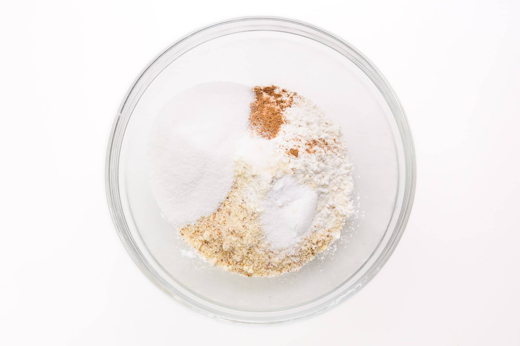 Dry ingredients to make donuts are in the bottom of a bowl.