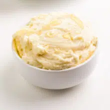 Honey butter is in a white bowl. There are drizzles of vegan honey on top.